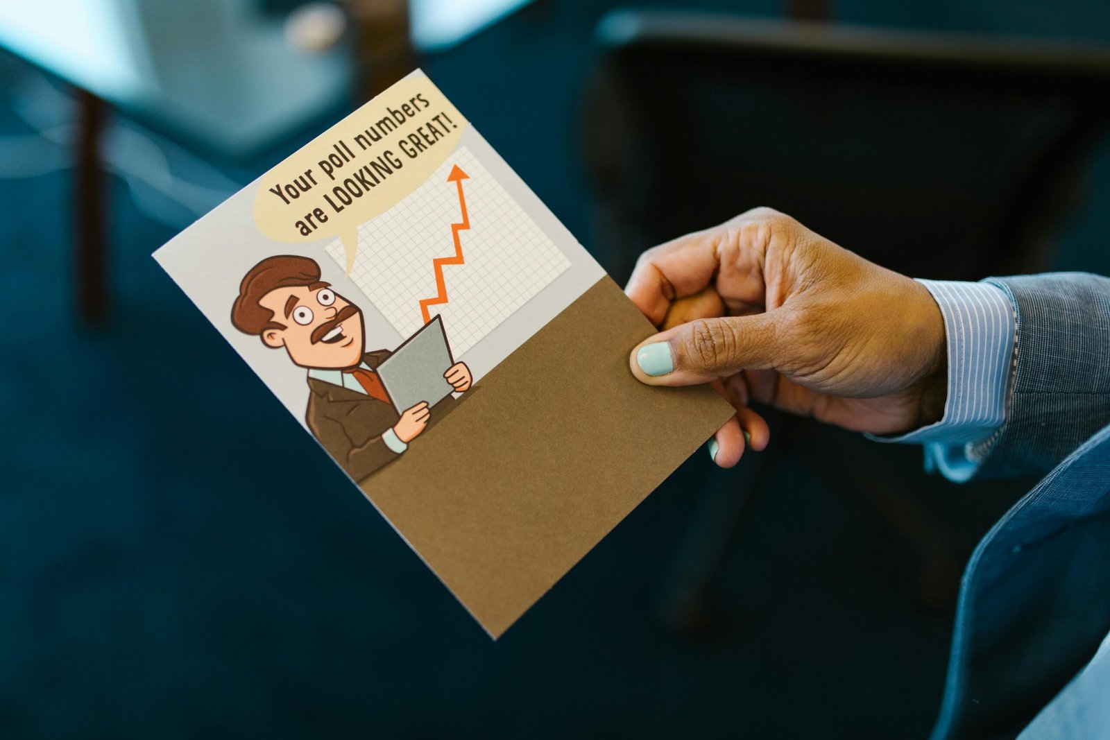 A person holding a humorous congratulatory card in an office setting.